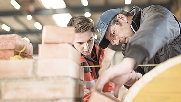 Auszubildender und Mentor begutachten Ziegel