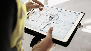 Ausbildung zum:zur Technische:r Systemplaner:in Ein STRABAG-Azubi mit einem Tablet auf der Baustelle