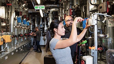 Zwei Kolleg:innen arbeiten an einer Anlage 