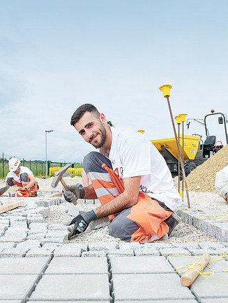 Foto Lehrling lehnt auf Spaten
