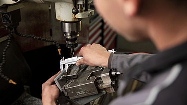 Foto Metall-Werkstatt Mann mit Schutzbrille schneidet Metallteile