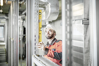 Ausbildung zur Bauwerksabdichtung Azubi steht vor einem Bauwerk mit digitalem Tool in der Hand