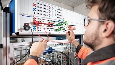 Junger Mann arbeitet an einem elektronischen Schaltkasten