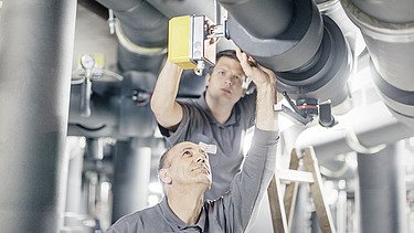 Zwei Männer arbeiten mit Messgerät an Rohrleitungen