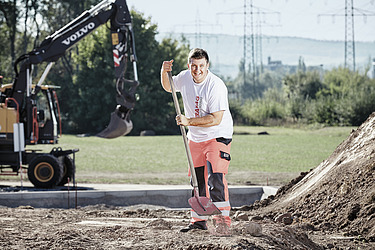 Foto Bauarbeiter kniet neben Plastersteinhaufen