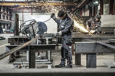 Foto zwei Arbeiter beim Bearbeiten von Metall
