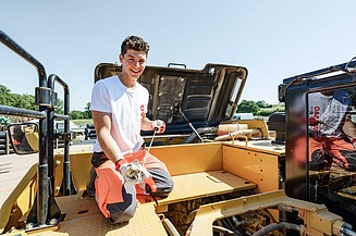 Ausbildung Baumaschinenmechatroniker Auszubildender arbeitet am Motor einer Baumaschine
