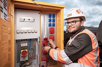 Auszubildender vor einem Verteilerkasten