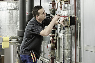 Ausbildung Mechatroniker:in Kältetechnik Mann arbeitet an der Isolierung von Rohren