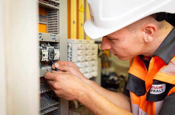 Junger Mann arbeitet an einem elektronischen Schaltkasten